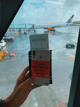Traveler holding a boarding pass with a plane visible through the window at Keflavík Airport.
