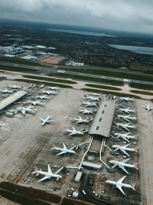 From above of modern airport terminal in industrial area with planes waiting for flight and launching on airfield