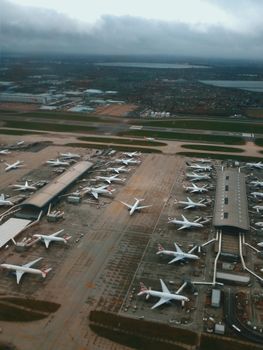 From above of aircrafts on airfield of terminal and waiting for launching and flight near green industrial area