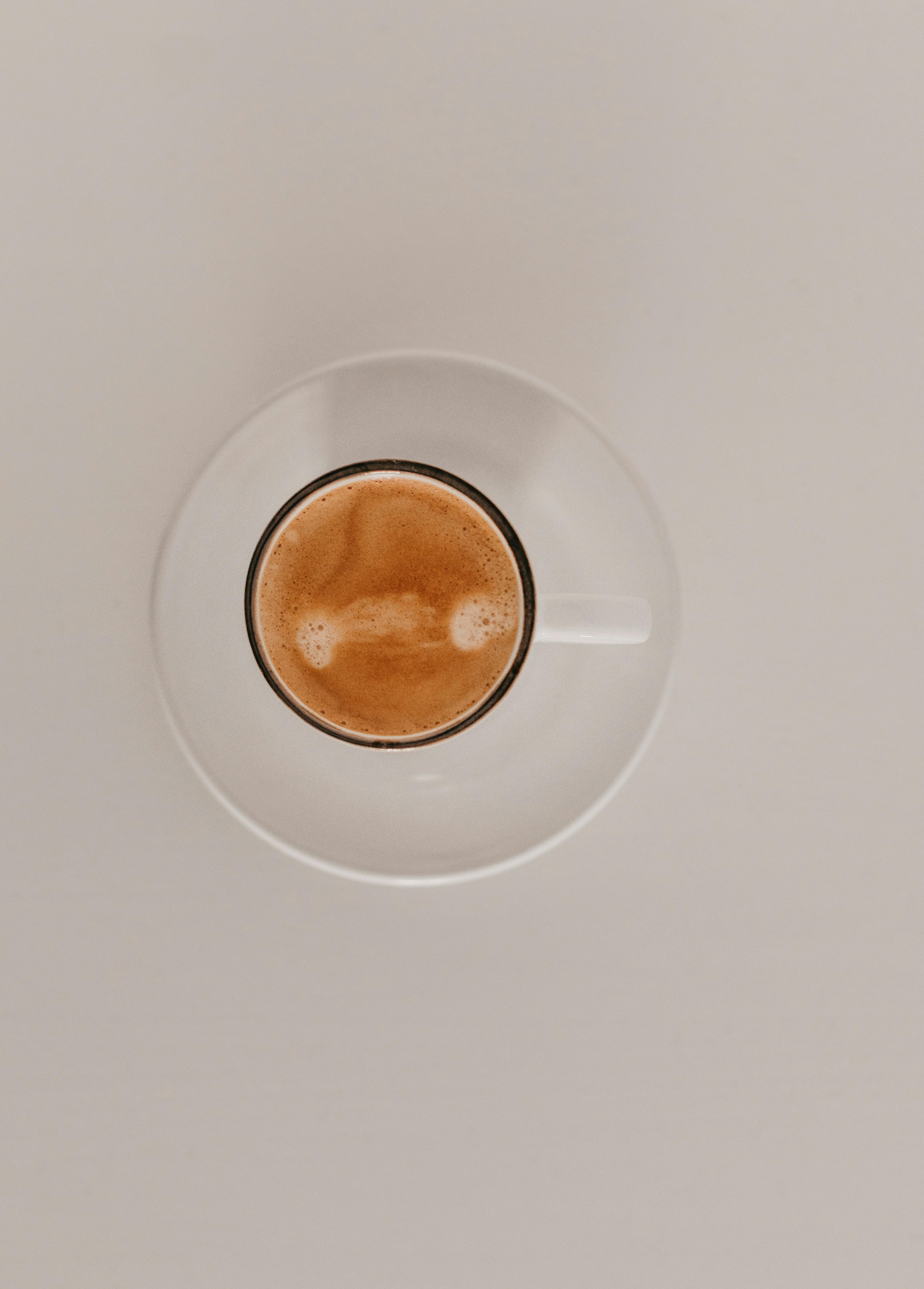 Elegant top-down shot of a cappuccino in a white cup with saucer, highlighting minimalist design and cozy vibes.