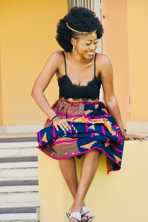 Stylish black female sitting on stairs and smiling