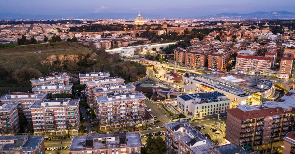 Aerial view of typical urban residential district with contemporary apartment houses and busy streets surrounded by mountains at evening