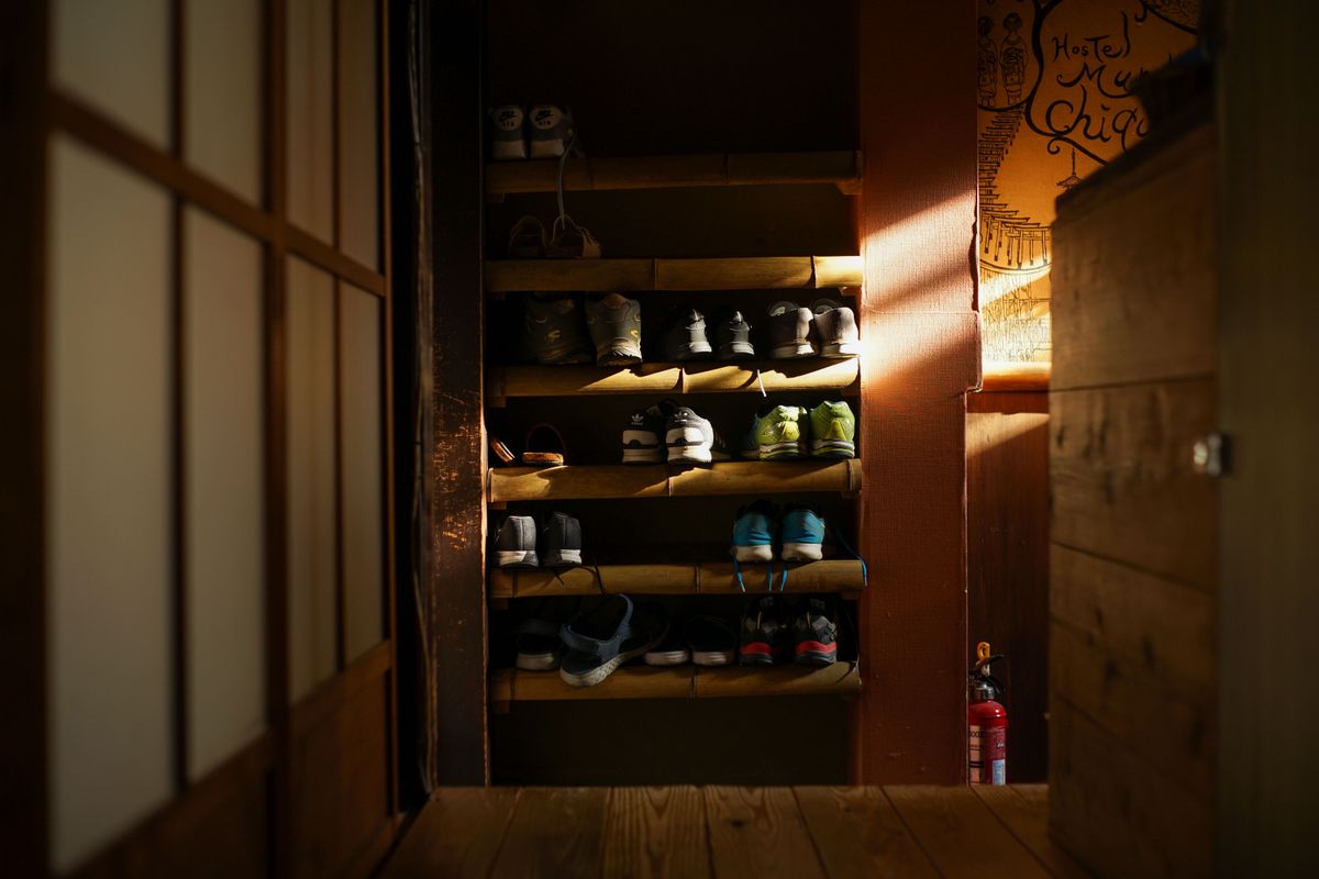 Warmly lit wooden shoe rack filled with organized footwear in a traditional home entryway