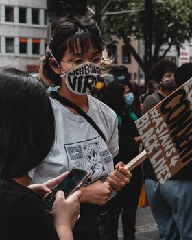 在德国科隆举行的“黑人生命也是命”抗议活动中，一名年轻女子戴着口罩，举着牌子