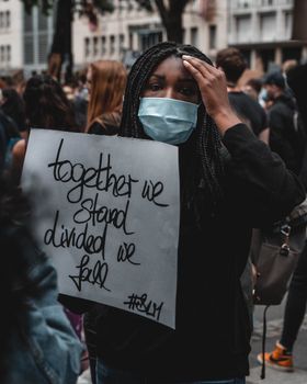 在科隆，“黑人生活问题”抗议者举着一个标语，上面写着“我们站在一起，分裂我们跌倒”