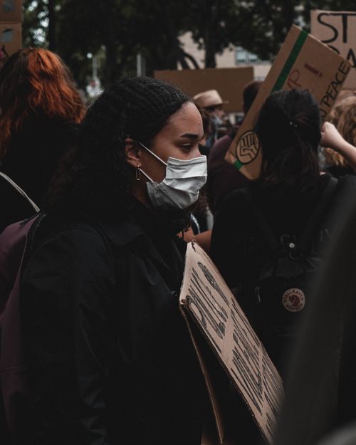 Free Young woman wearing a mask during a protest amidst the covid-19 pandemic. Stock Photo