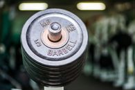 Metal weight plates on bar placed in contemporary fitness center against blurred gym equipment