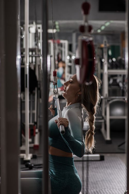 Free Fit woman exercising on arm machine in gym Stock Photo