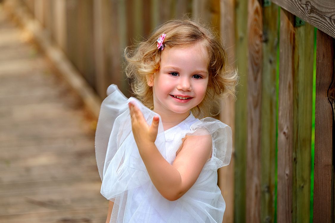 Happy little girl in white dress on wooden terrace · Free Stock Photo