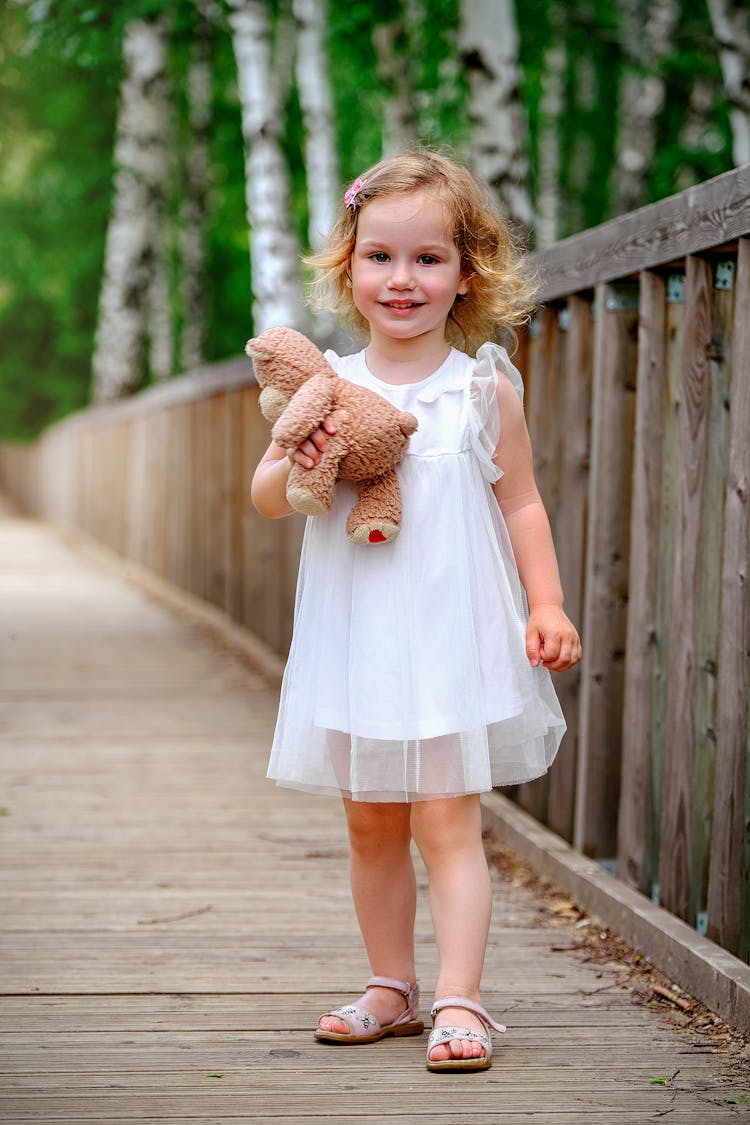 Charming Little Girl With Toy On Wooden Bridge