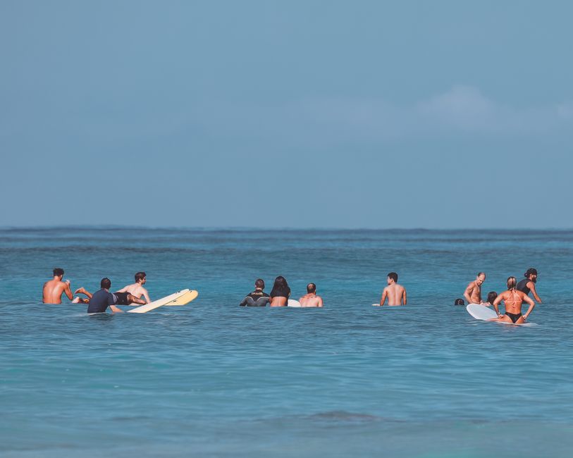 A group of surfers relax on their boards in the calm ocean waters at Waikiki Beach, Honolulu.