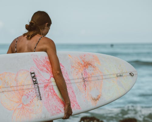 Woman in Pink and White Surfboard on Sea