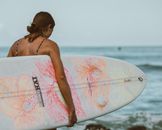 夏威夷檀香山的沙滩上，一个冲浪女孩带着五颜六色的冲浪板