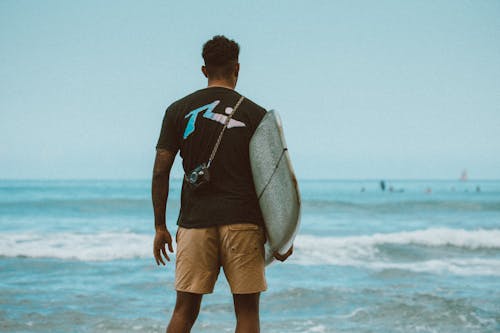 Man in Black and White Nike Crew Neck T-shirt and Brown Shorts Standing on Beach