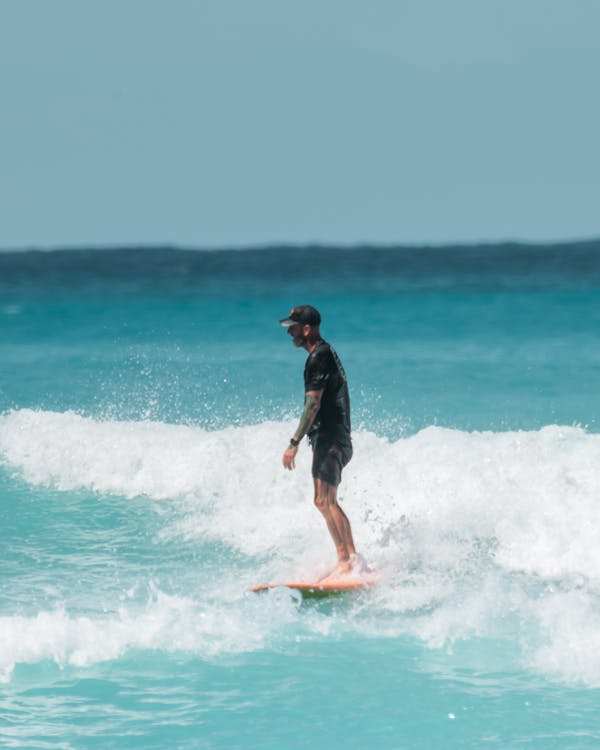 Man in Black Wet Suit Surfing on Sea Waves