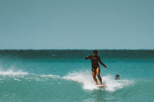 Woman in Black Bikini Surfing on Sea Waves