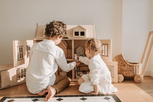 Free Back View of Kids Playing with a Dollhouse Stock Photo