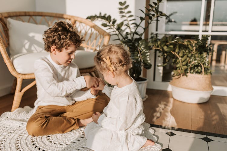 A Boy And A Girl Playing While Sitting On The Floor