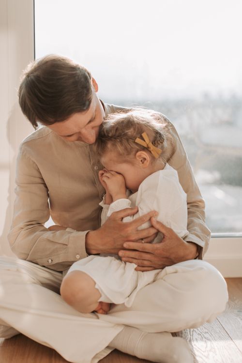 Free A tender moment between a father and daughter sitting by the window, filled with love and comfort. Stock Photo