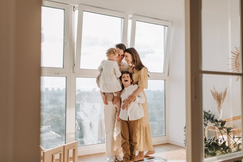 Free A Happy Family Standing by the Window Stock Photo