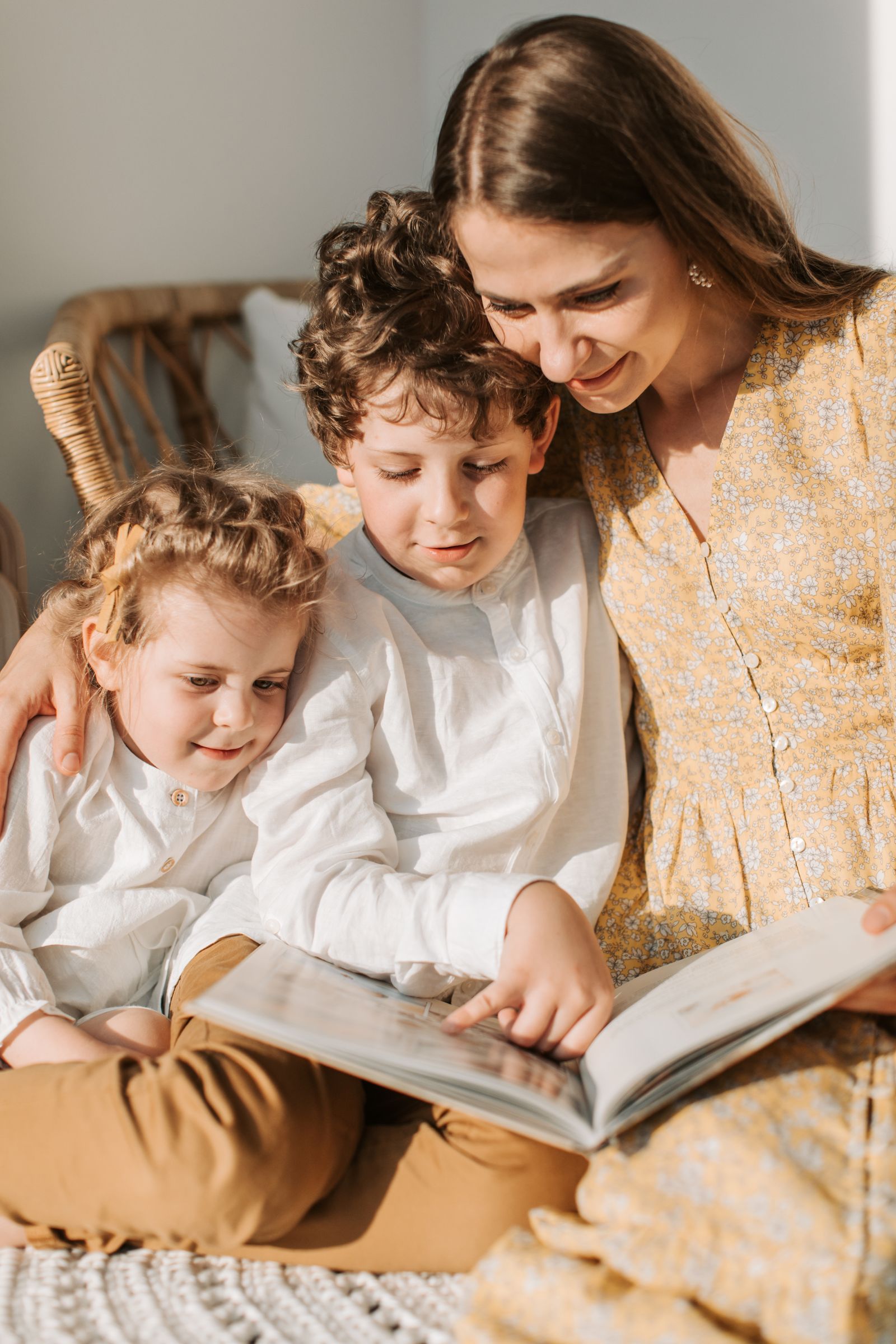 A mother and two children sharing a picture book during a warm family reading moment