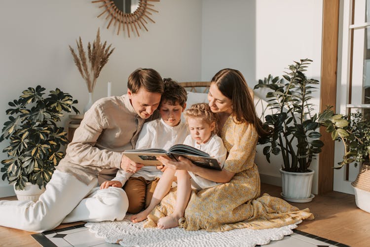 A Family Sitting On Floor Reading A Book