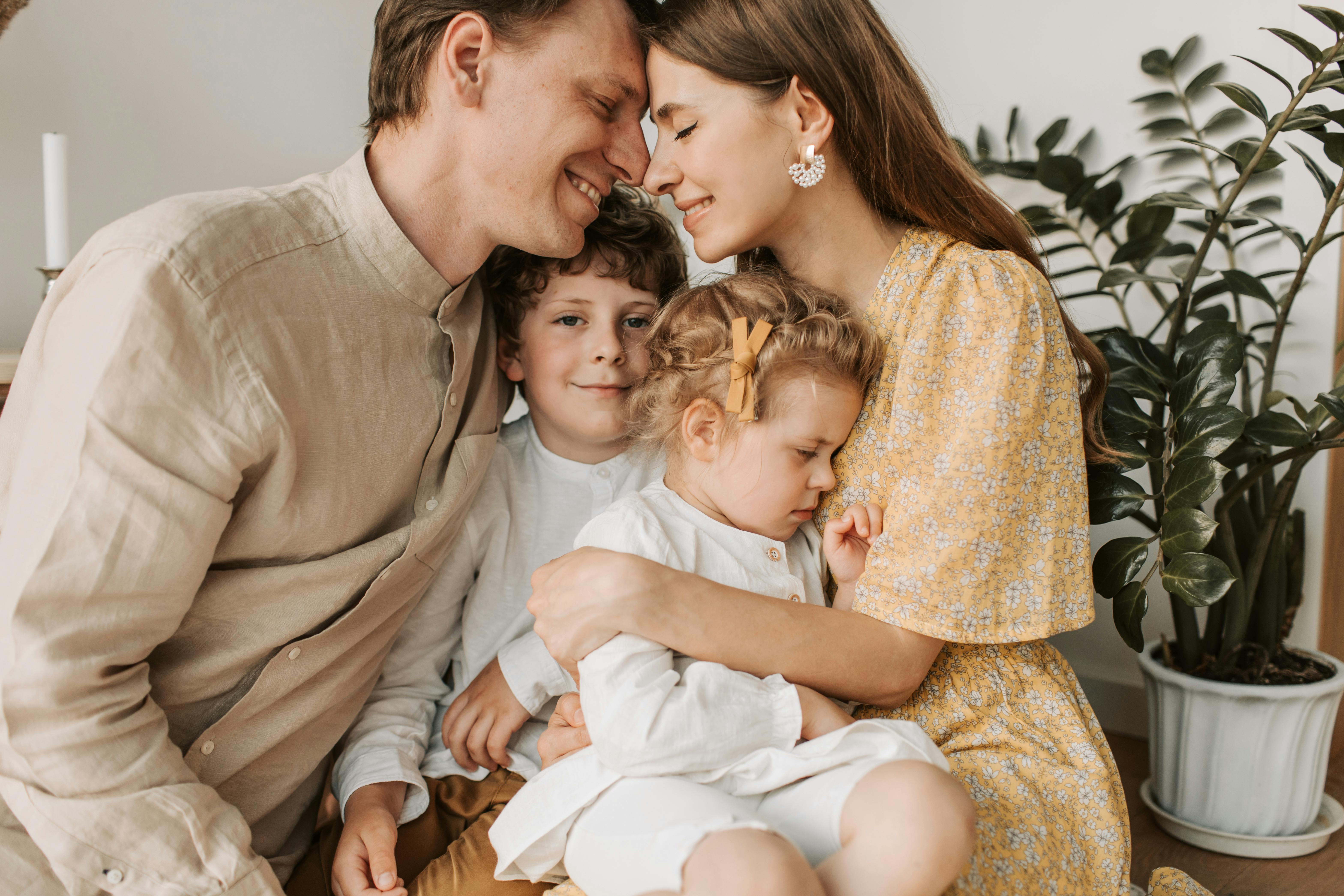 a couple rubbing their noses together while hugging their kids