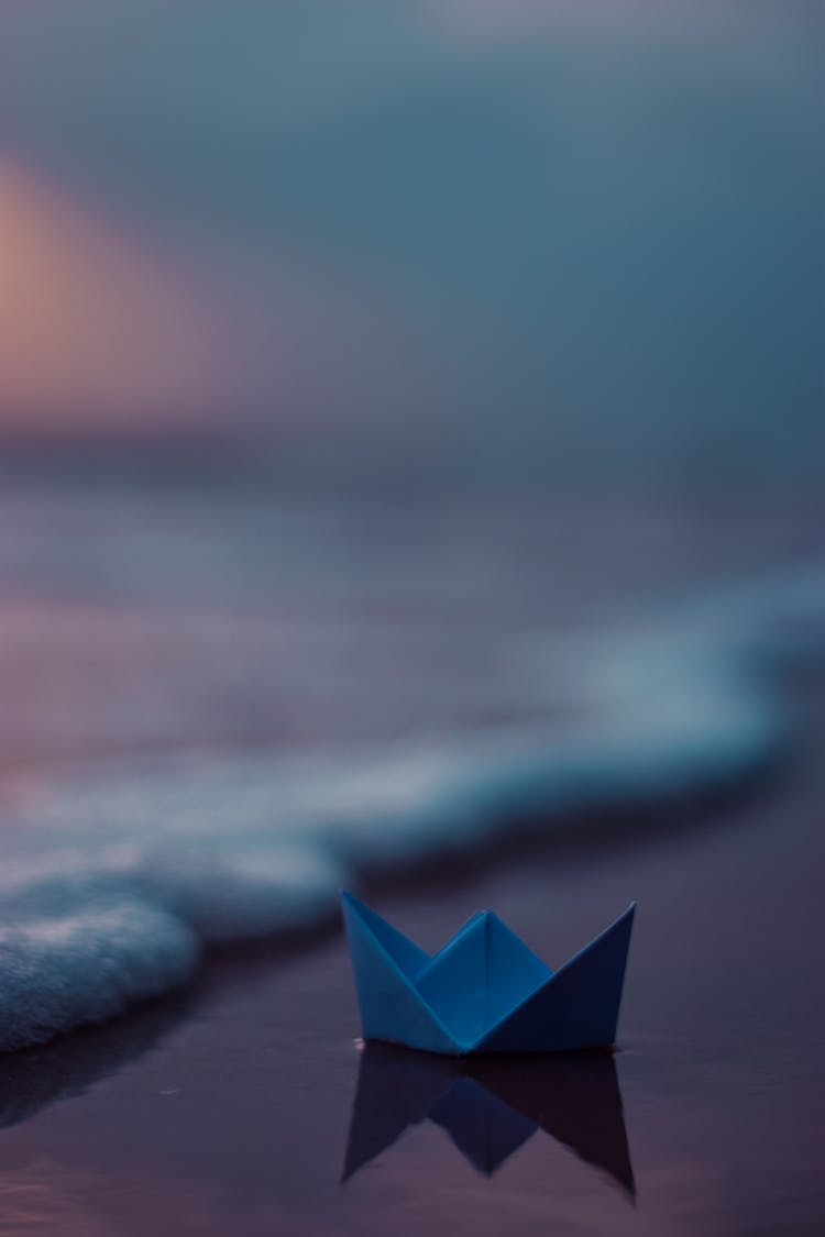 Paper Origami Boat On Wet Beach