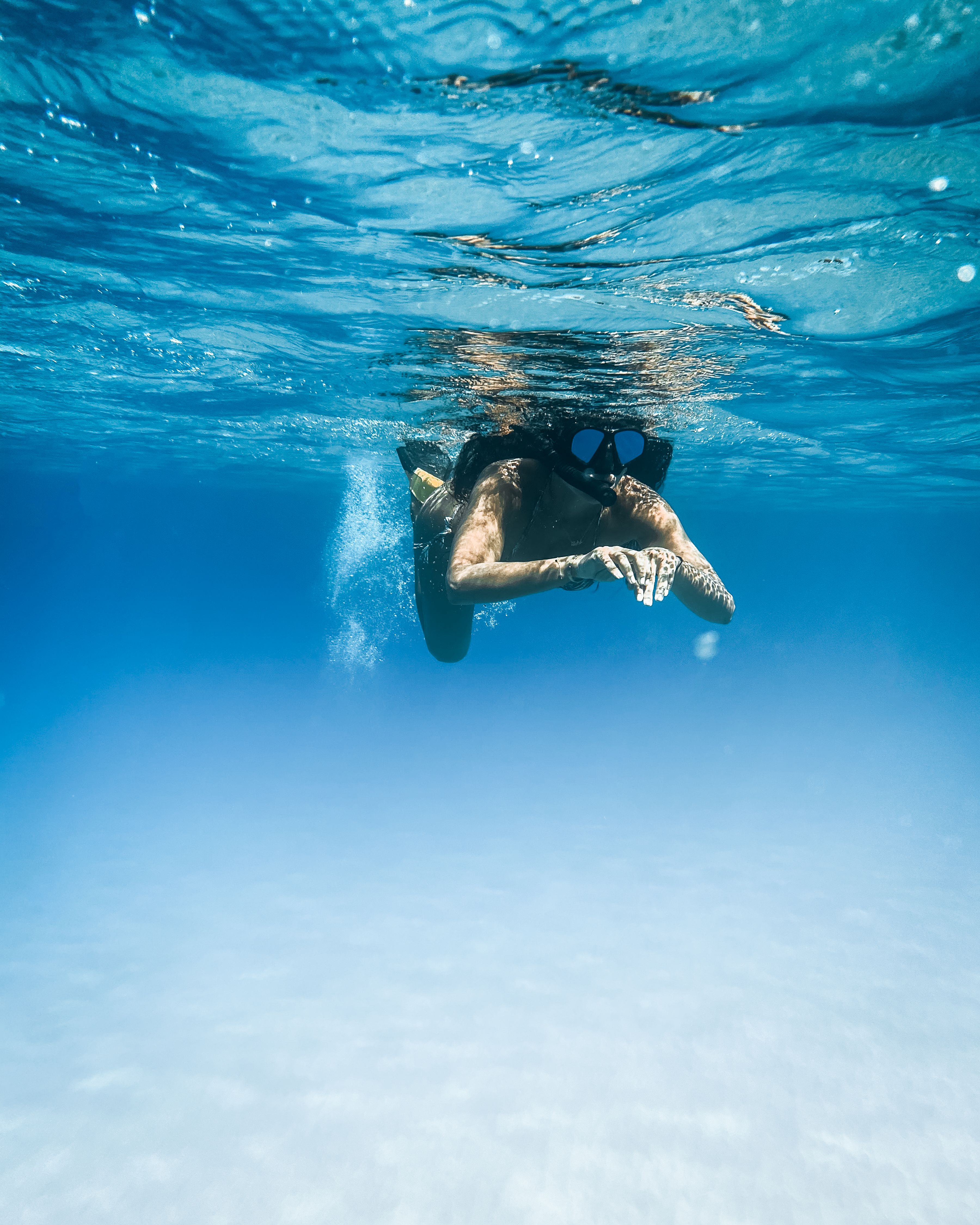 一个女人在夏威夷清澈的蓝色海洋中浮潜，观察着宁静的海洋生物