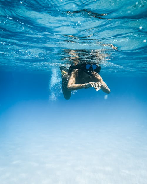 Woman in Black Bikini Swimming in Blue Water