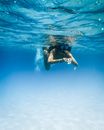 一个女人在夏威夷清澈的蓝色海洋中浮潜，观察着宁静的海洋生物