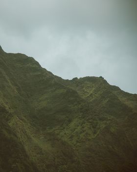 夏威夷多云天空下，郁郁葱葱的绿色山脉景色壮丽