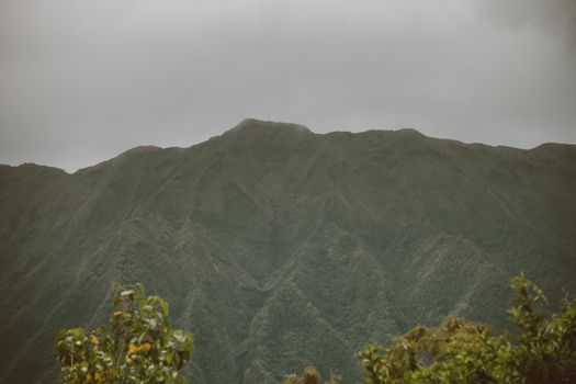 夏威夷檀香山的风景中，郁郁葱葱的绿色山脉映衬着灰色的天空