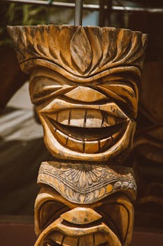Close-up of a traditional tiki sculpture with intricate carvings and a smiling face in Hawaii.