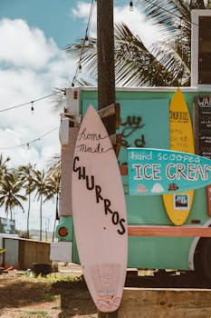 Colorful Hawaiian food truck with churros and ice cream offerings under palm trees.