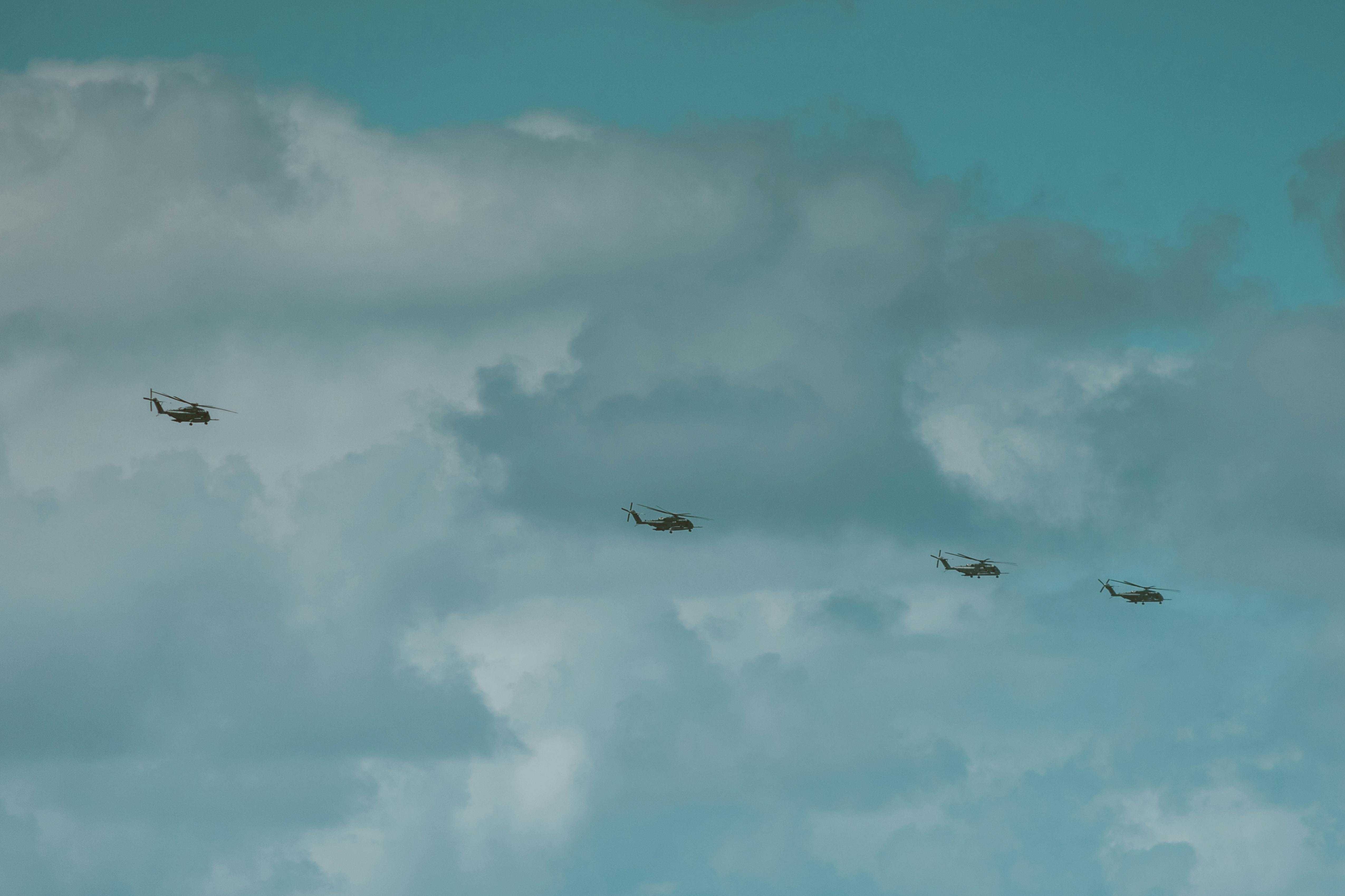 Aerial view of helicopters in formation beneath a dramatic cloudy sky, captured in Hawaii.
