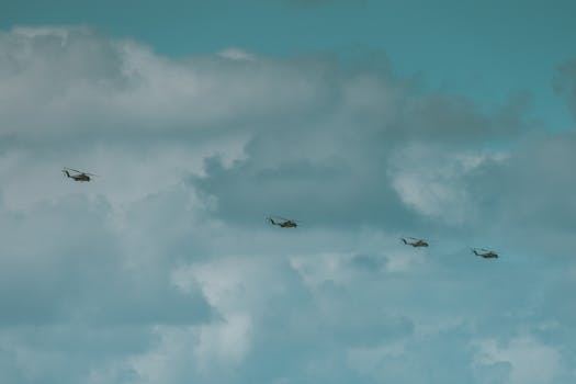 Aerial view of helicopters in formation beneath a dramatic cloudy sky, captured in Hawaii.