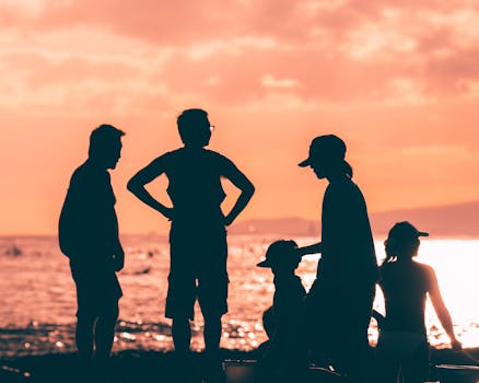 Silhouettes of a family by the sea during a stunning orange sunset.