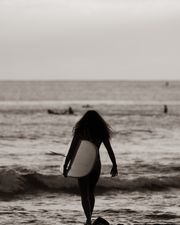 Surfer carrying a board into the shore break, photo by Jess Loiterton on Pexels