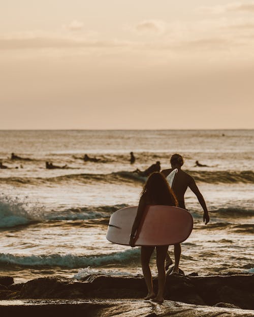 Man Carrying White Surfboard on Beach