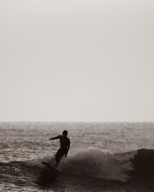 Free Silhouette of a surfer riding a wave in Honolulu, Hawaii, capturing the thrill and beauty of ocean sports. Stock Photo