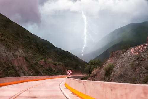 Free Thunderstorm over road between green mountains Stock Photo