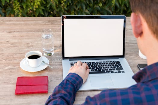 Adult working on laptop outdoors with coffee and notepad, promoting remote work flexibility.