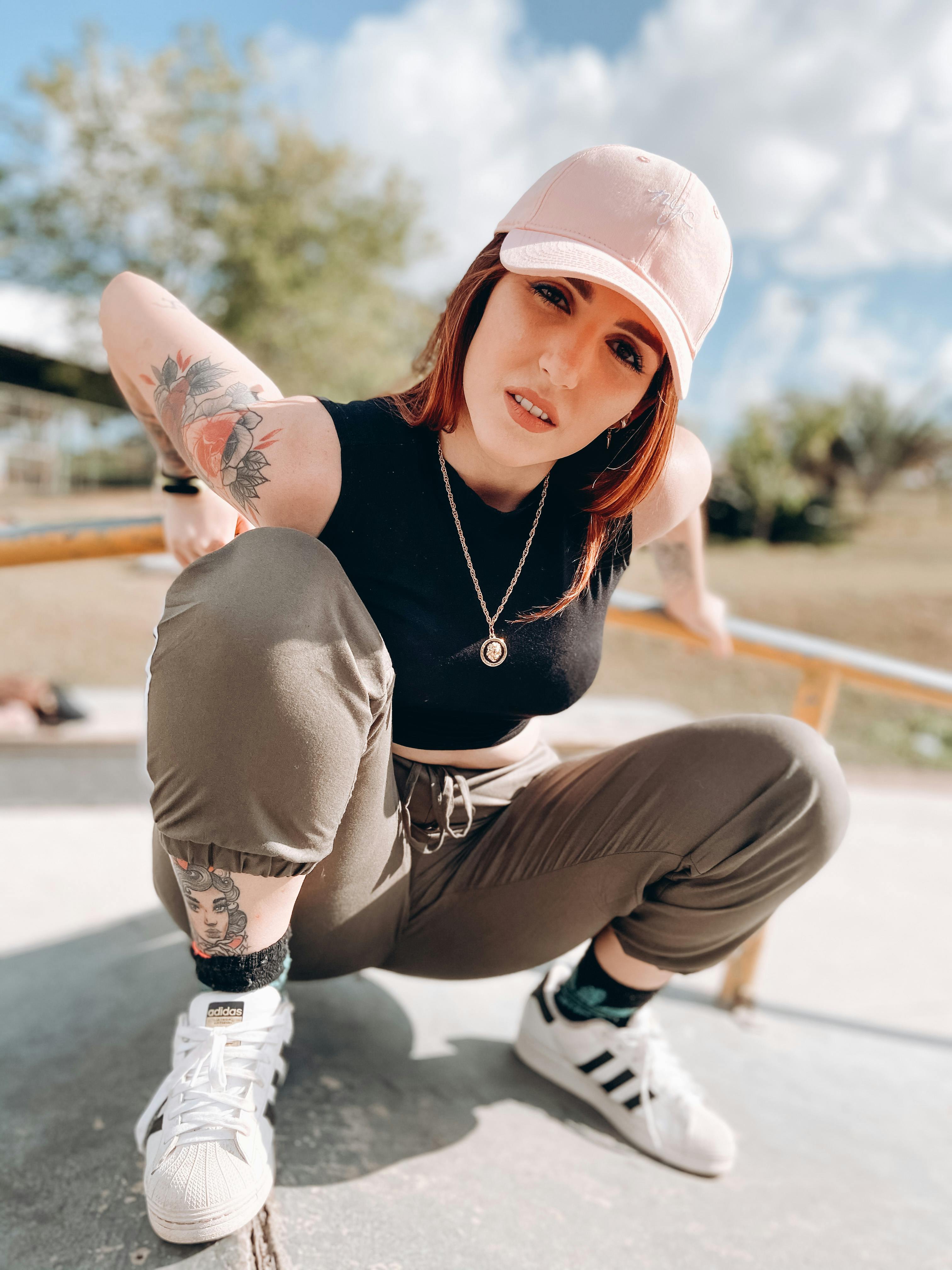 Trendy female millennial sitting on haunches in skate park Photo