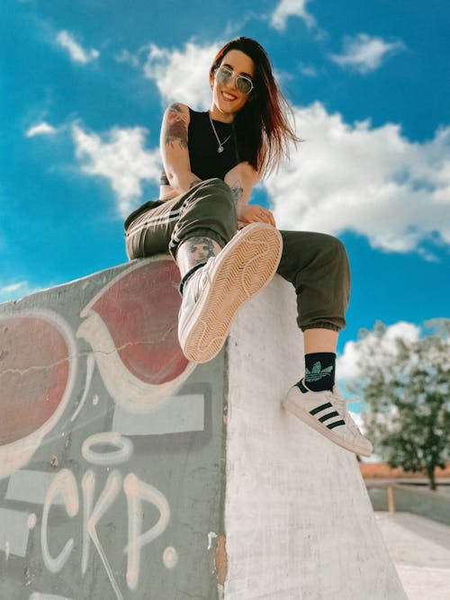 Trendy young female skater resting on concrete ramp after training