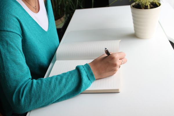 Writer drafting notes at a white desk — photo by Pixabay on Pexels
