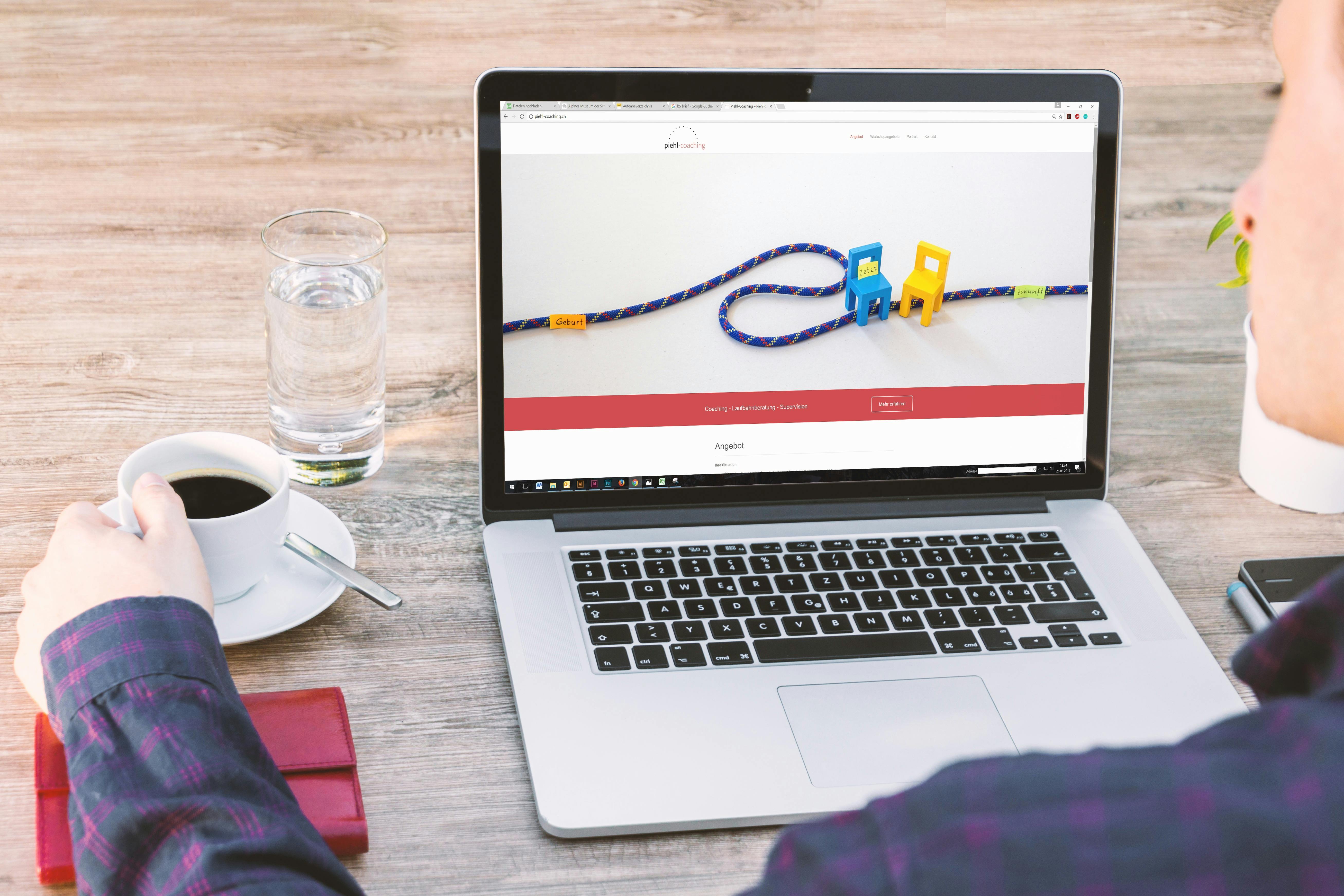 person holding a cup of coffee beside macbook