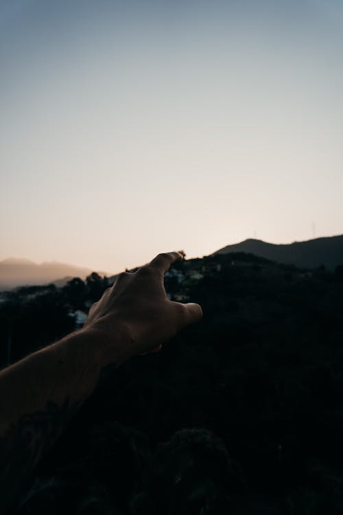Crop hiker with outstretched hand against mountains at sundown
