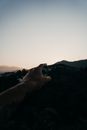 Crop hiker with outstretched hand against mountains at sundown