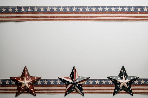 Star shaped souvenirs and ribbons with American flag pattern placed on white table